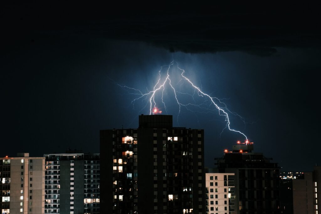 Raio atingindo o topo de um edifício corporativo durante uma tempestade noturna.
