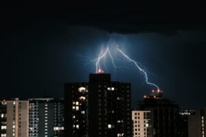 Raio atingindo o topo de um edifício corporativo durante uma tempestade noturna.