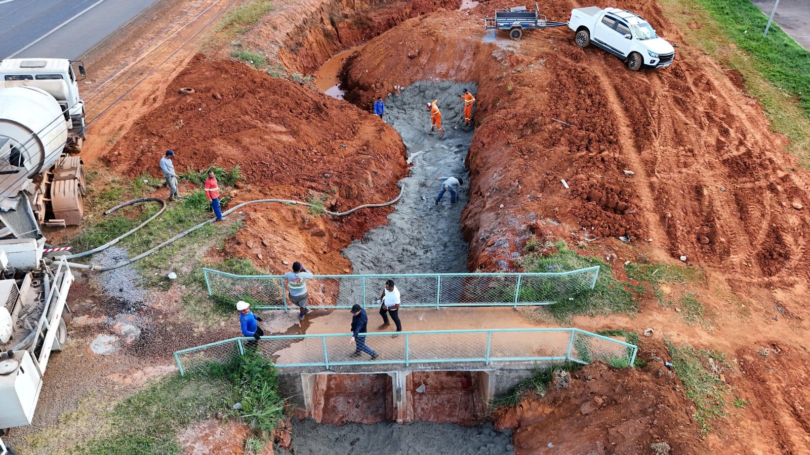 Obra de drenagem pluvial e concretagem de canal de escoamento para contenção de erosão.